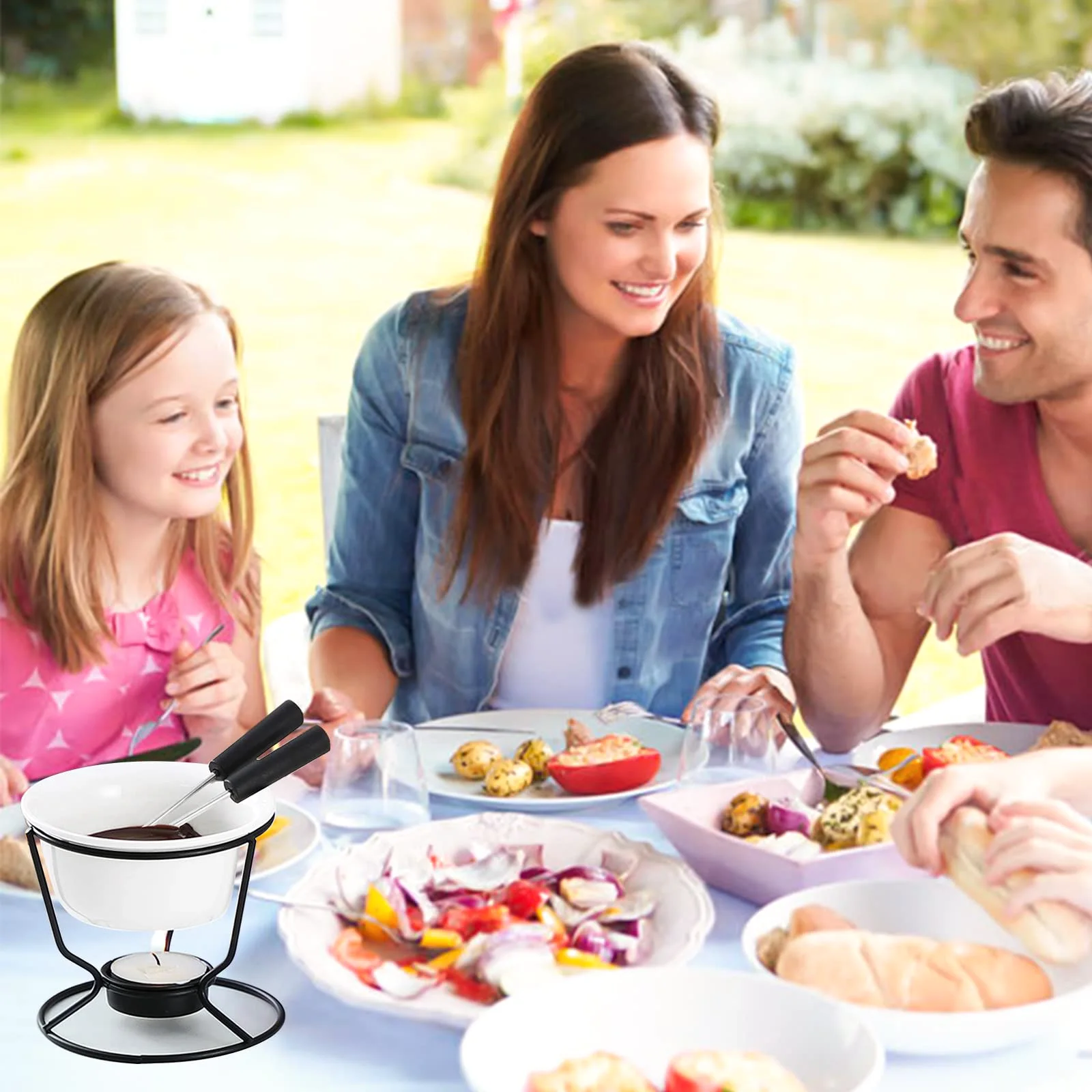 A family at an outdoor table, with a Luvan warmer of melted chocolate and two fondue forks over a tealight.